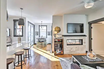 a living room with a fireplace and a table at Modern Mountain Getaway, Walk to Grand Lake! in Grand Lake