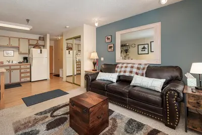 a living room with a leather couch and a kitchen at Snowblaze E102 Studio in Winter Park