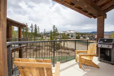 a balcony with a stove and two wooden chairs at Trailhead Lodges Building 101 Unit 131 in Winter Park