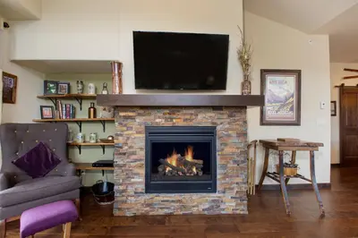a living room with a fireplace with a flat screen tv at Trailhead Lodges Building 101 Unit 131 in Winter Park
