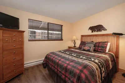 a bedroom with a bed and a dresser and a television at Beaver Village Unit #0333 in Winter Park