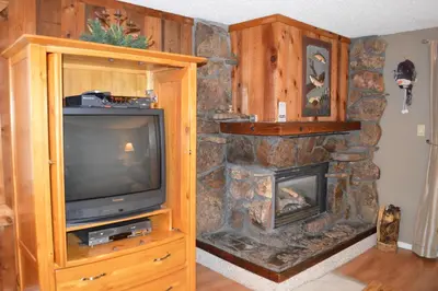 a living room with a tv and a stone fireplace at Beaver Village Unit #0521R in Winter Park