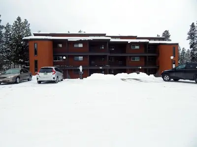 a building with cars parked in a snow covered parking lot at Beaver Village Unit #0521 in Winter Park