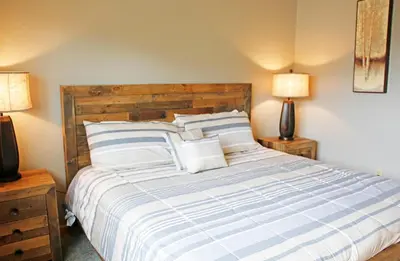 a bedroom with a bed with striped sheets and two lamps at Meadow Ridge Court 8 Unit 6 in Fraser
