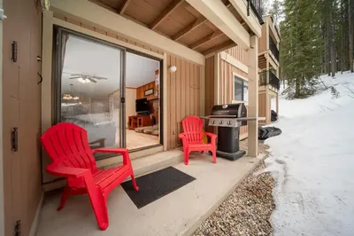 two red chairs sitting on a porch with a grill at Beaver Village Unit #0412 in Winter Park