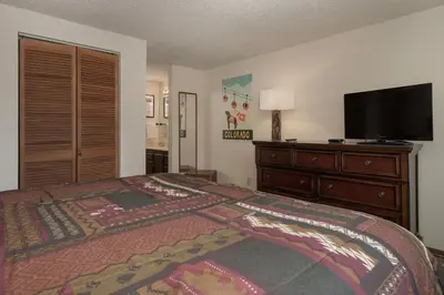 a bedroom with a bed and a dresser with a flat screen tv at Beaver Village Unit #0623R in Winter Park
