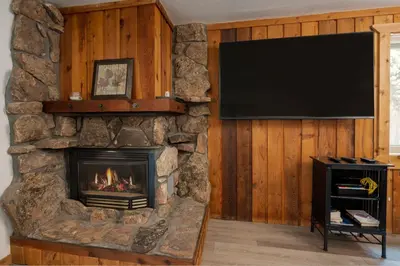 a living room with a stone fireplace and a flat screen tv at Beaver Village Unit #0514 in Winter Park