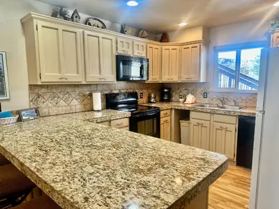 a kitchen with white cabinets and a granite counter top at Hi Country Haus Unit 1801 in Winter Park