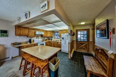 a kitchen with wooden cabinets and a wooden table at Hi Country Haus Unit 2201 in Winter Park
