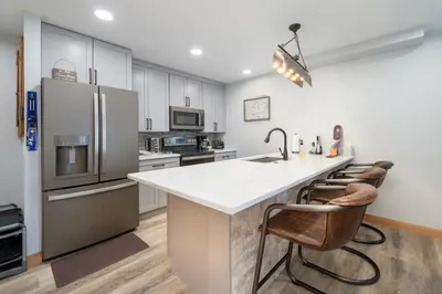 a kitchen with a large white counter and chairs at Silverado I Building A Unit 101 in Winter Park