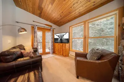 a living room with two leather chairs and a television at Creekside Unit 403 in Winter Park