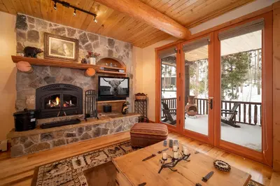 a living room with a stone fireplace and a table at 500 North Lupine in Fraser