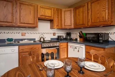 a kitchen with wooden cabinets and a wooden table with chairs at Hi Country Haus Unit 0309 in Winter Park