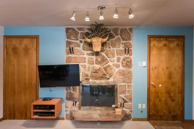 a living room with a stone wall with a fireplace at Hi Country Haus Unit 2501 in Winter Park