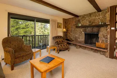 a living room with a stone fireplace and a table at Hi Country Haus Unit 2111 in Winter Park