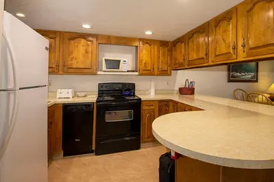 a kitchen with wooden cabinets and a white refrigerator at Hi Country Haus Unit 2111 in Winter Park