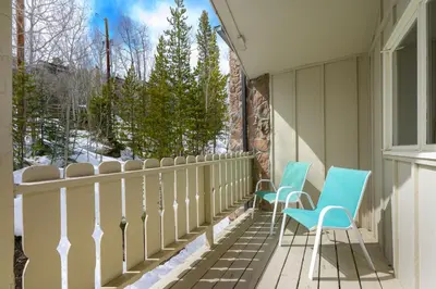 two blue chairs sitting on a porch with a window at Hideaway Village Alpine 4 in Winter Park