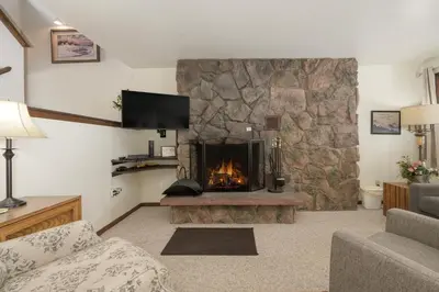 a living room with a large stone fireplace at Hideaway Village Alpine 4 in Winter Park