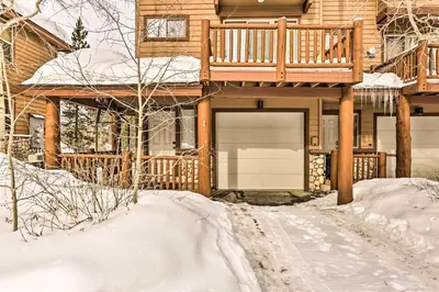 a house with a garage in the snow at Winter Park Townhome with Hot Tub, Ski Shuttle! in Winter Park