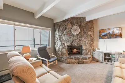a living room with a stone wall with a fireplace at Lake View Condo: Walk To Downtown/Lake Dillon in Dillon