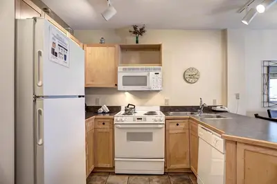 a kitchen with white appliances and wooden cabinets at Silver Mill 8200 - 1Br-Walk to Slopes! Kids Ski Free! condo in Keystone