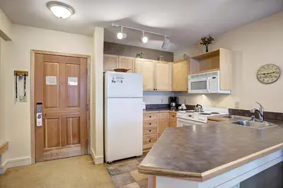 a kitchen with a white refrigerator and a sink at Silver Mill 8200 - 1Br-Walk to Slopes! Kids Ski Free! condo in Keystone