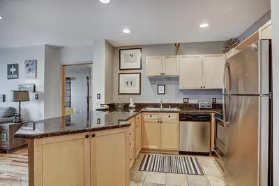 a kitchen with wooden cabinets and a stainless steel refrigerator at Premier Silver Mill 8281 - 2Br-Walk to Slopes! Kids Ski Free! condo in Keystone
