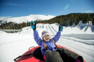 a woman is laying in the snow on a snowboard at Premier Silver Mill 8281 - 2Br-Walk to Slopes! Kids Ski Free! condo in Keystone