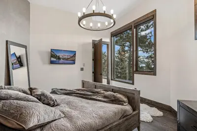 a bedroom with two beds and a chandelier at Skyes Peak - Luxury Mountain Retreat with Breathtaking Views in Estes Park