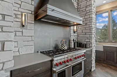 a kitchen with a stove and a stone wall at Skyes Peak - Luxury Mountain Retreat with Breathtaking Views in Estes Park