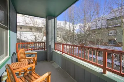 a porch with two wooden chairs and a balcony with snow at Silver Mill 8167 - 1Br-Walk to Slopes! Kids Ski Free! condo in Keystone