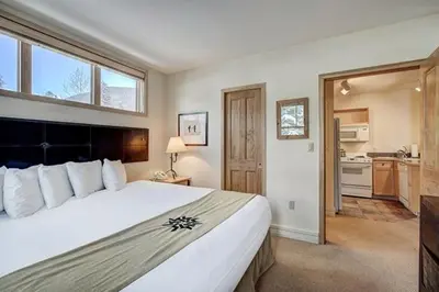 a bedroom with a large white bed and a kitchen at Silver Mill 8184 - 1Br-Walk to Slopes! Kids Ski Free! condo in Keystone