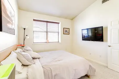 a white bedroom with a bed and a flat screen tv at 4 Mi to Airport Convenient Denver Condo in Aurora