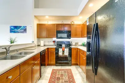 a kitchen with wooden cabinets and a stainless steel refrigerator at 4 Mi to Airport Convenient Denver Condo in Aurora