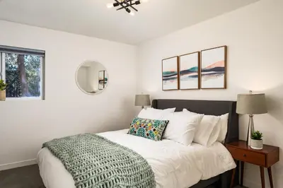 a white bedroom with a bed with a green blanket at The Modern Mountaineer in Bailey