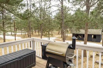 a gun sitting on a wooden deck with a bench at The Modern Mountaineer in Bailey