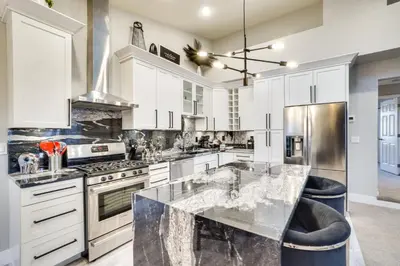 a kitchen with white cabinets and a marble counter top at Near Red Rocks Golden Getaway with Deck! in Golden