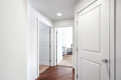 an open door to a hallway with white walls and wooden floors at Fully Furnished 2BR Centrally Located with Pool in Greeley