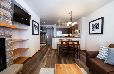 a living room and kitchen with a couch and a table at Secluded Condo with Corridor Ski Trail View - Zephyr Mountain Lodge Premium Unit 1201 condo in Winter Park