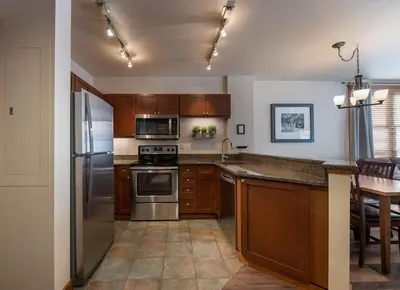 a kitchen with wooden cabinets and stainless steel appliances at Secluded Condo with Corridor Ski Trail View - Zephyr Mountain Lodge Premium Unit 1201 condo in Winter Park