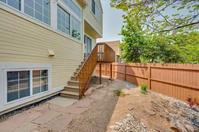 a house with a wooden staircase next to a fence at 13 Mi to Dtwn Denver Arvada Townhome with Deck in Arvada