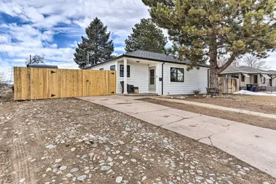 a house with a wooden fence in front of a driveway at 3 Mi to Empower Field Denver Home with Fire Pit in Denver
