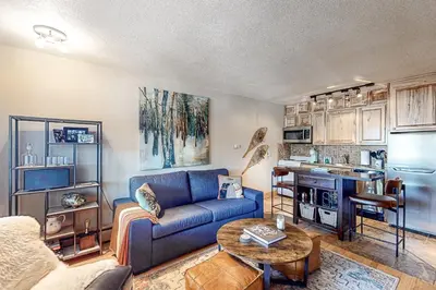 a living room with a blue couch and a table at High Country Nest in Winter Park- Unit 16 in Winter Park