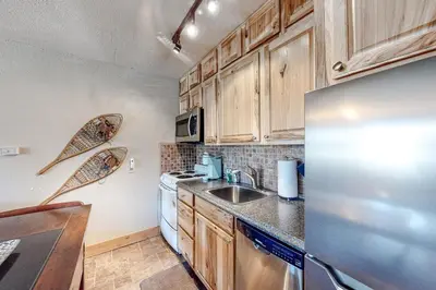 a kitchen with wooden cabinets and a stainless steel refrigerator at High Country Nest in Winter Park- Unit 16 in Winter Park
