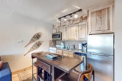 a kitchen with wooden cabinets and a stainless steel refrigerator at High Country Nest in Winter Park- Unit 16 in Winter Park