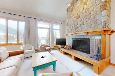 a living room with a large stone fireplace at Rocky Mountain Living in Dillon
