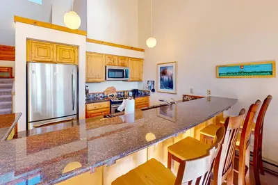 a kitchen with a large counter with chairs and a refrigerator at Rocky Mountain Living in Dillon