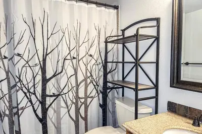a bathroom with a shower curtain with trees on it at Griffons Nest in Silverthorne
