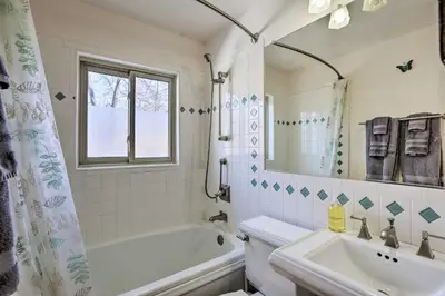 a bathroom with a tub and a sink and a mirror at 5 Mi to Dtwn Denver Peaceful Lakewood Home! in Lakewood