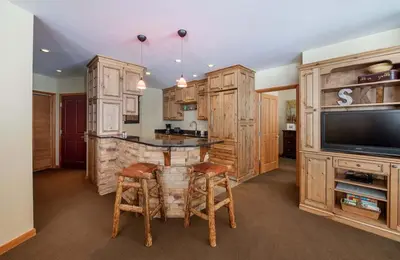 a kitchen with wooden cabinets and a bar with stools at Zephyr Mountain Lodge, Condo - 3 Bedroom Select-Rated Condo 1609 condo in Winter Park